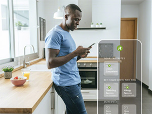 Young Man Using Cell Phone In Kitchen At Home